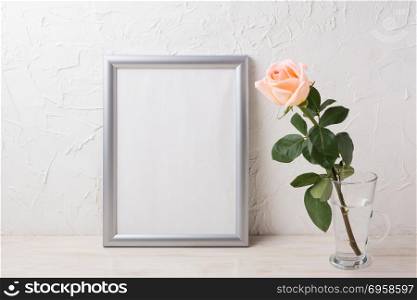Silver frame mockup with creamy pink rose in glass vase. Empty frame mock up for presentation artwork.. Silver frame mockup with creamy pink rose in glass vase