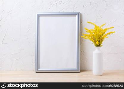 Silver frame mockup with ornamental yellow flowering grass in vase. Empty frame mock up for presentation artwork.. Silver frame mockup with ornamental yellow flowering grass in va