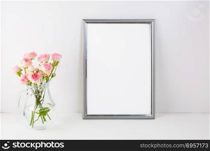 Silver frame mockup with pink roses. Portrait or poster white frame mockup. Empty white frame mockup for presentation artwork.. Silver frame mockup with pink roses
