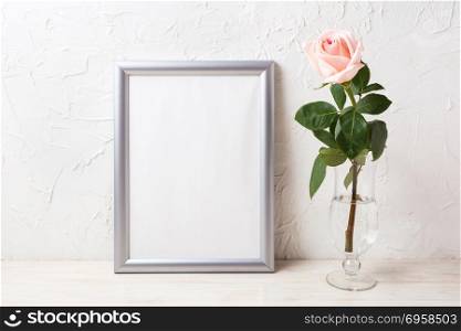 Silver frame mockup with soft pink rose in exquisite vase. Empty frame mock up for presentation artwork.. Silver frame mockup with soft pink rose in exquisite vase