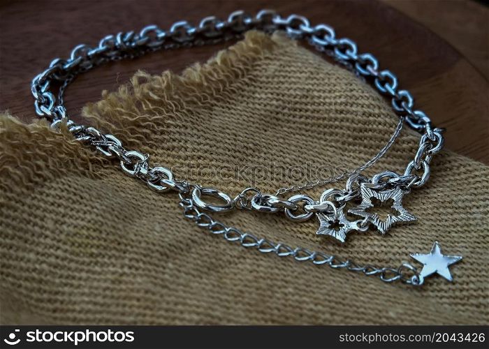 Silver jewelry fashion photography. Silver necklace fashion photography. Necklace presented on brown sackcloth. Women accessories. Focus and blur.
