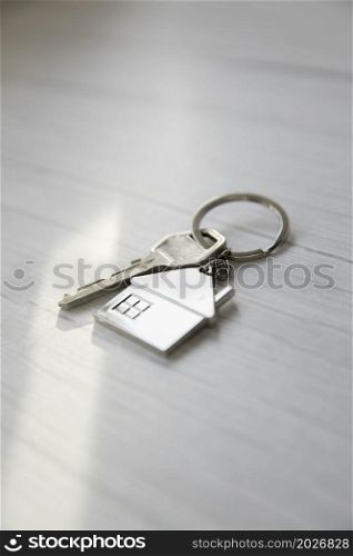 Silver key with silver house figure on white wooden background, buying new house real estate concept copy space top view. Silver key with silver house figure on white wooden background, buying new house real estate concept copy space
