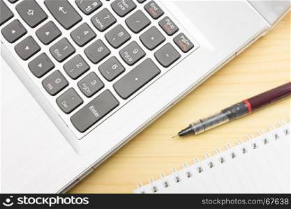 Silver laptop and notebook and pen on wood table. Business concept background