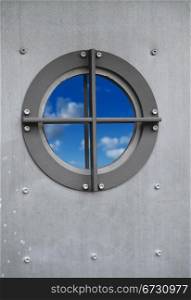 Silver metal door with porthole window with view on sky