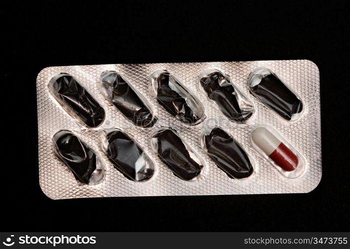 Silver package of pills spent on a black background