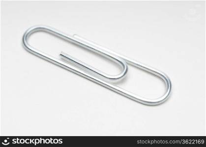Silver paper clip on white background