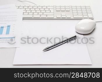 Silver pen and paper on office desk keyboard with mouse