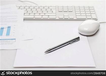 Silver pen and paper on office desk keyboard with mouse