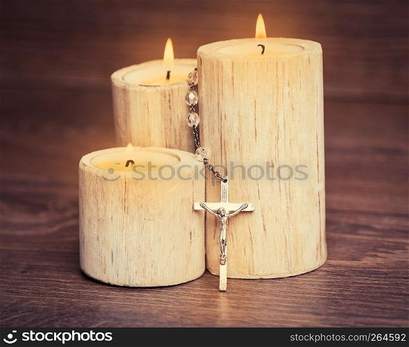 Silver rosary with Jesus on the Candle at wooden table,religion concept,vintage style with split toning.
