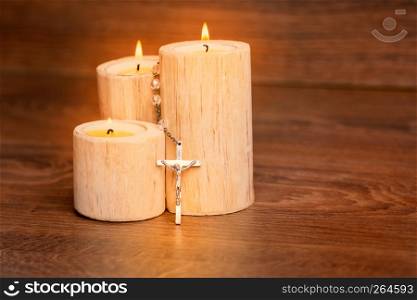 Silver rosary with Jesus on the Candle at wooden table,religion concept,vintage style.
