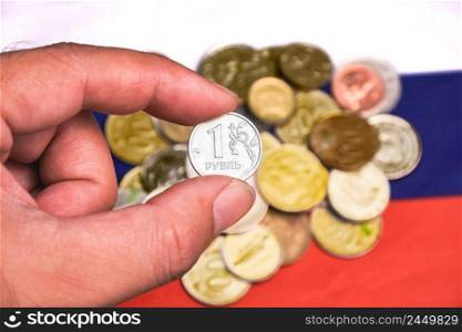 Silver ruble coin on the hand with ruble coins stack and the flag of Russia on background