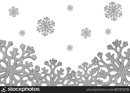 Silver shiny snowflakes fall over a white background