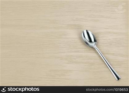 Silver spoon on wooden table, top view
