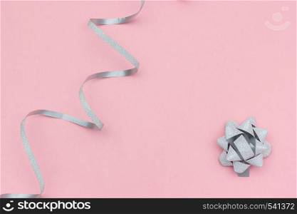 Silver streamers serpentine and bow on pink background in minimal style. Concept decorations for celebration, party, holiday, Christmas, birthday, new year Template for text or design. Copy space.. Silver streamers serpentine and bow on pink background in minimal style. Concept decorations for celebration, party, holiday, Christmas, birthday, new year Template for text or design. Copy space