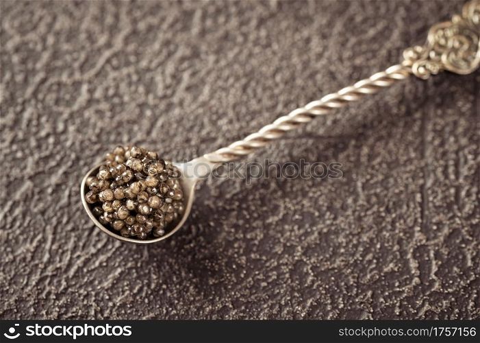 Silver teaspoon of black caviar close up