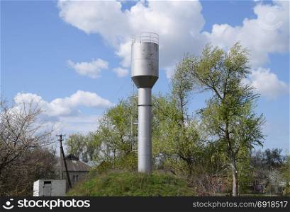 Silver Water Tower among green grass and trees.. Silver Water Tower among green grass and trees