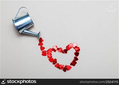 silver watering can flowers pouring hearts on light beige background. Valentines background, love, date concept. silver watering can pouring hearts on a light beige background. Valentines background, love, date concept