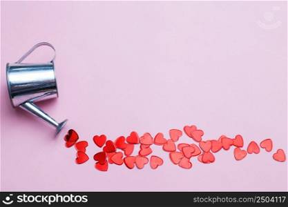 silver watering can flowers pouring hearts on pink background. Valentines background, love, date concept. silver watering can pouring hearts on a pink background. Valentines background, love, date concept
