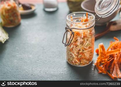 Simple fresh carrot cabbage salad in jars for healthy lunch is on kitchen table background, front view, with copy space. Vegetarian food, low-calorie vegetable eating and weight loss dieting concept