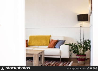 Simple, industrial interior design of living room with wooden table standing in front of a gray sofa with yellow and blue cushions and a green plant scandinavian interior new. Simple, industrial interior design of living room with wooden table standing in front of a gray sofa with yellow and blue cushions and a green plant scandinavian interior