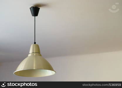 Simple lamp with white lampshade on black cable wire hanging on ceiling.. White lamp hanging on ceiling