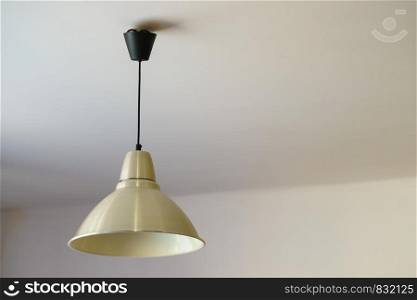 Simple lamp with white lampshade on black cable wire hanging on ceiling.. White lamp hanging on ceiling