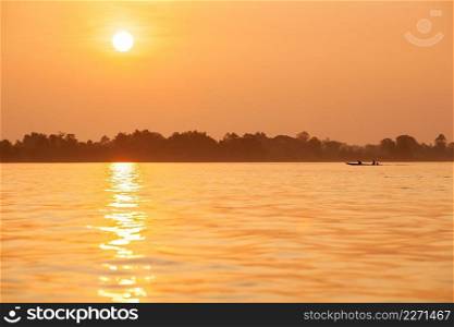Simple life, golden light shines down around the Mekong River, fishing boat returning home in the evening. Don Khon Island, Si Phan Don, Ch&asak, South Laos. Summer season. Warm tone. Copy space.