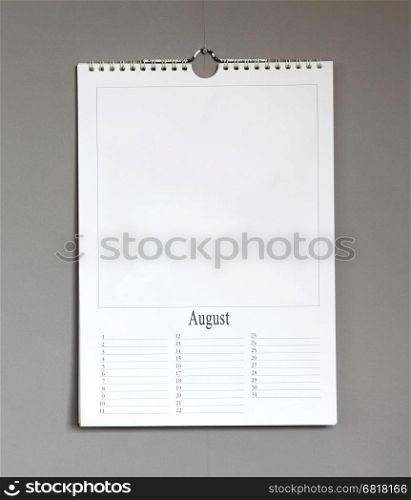 Simple old birthday calendar hanging on a grey wall, copy space - August