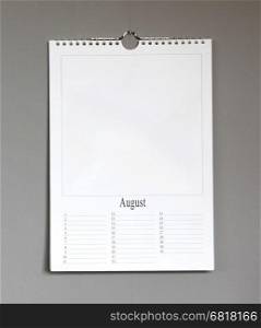 Simple old birthday calendar hanging on a grey wall, copy space - August