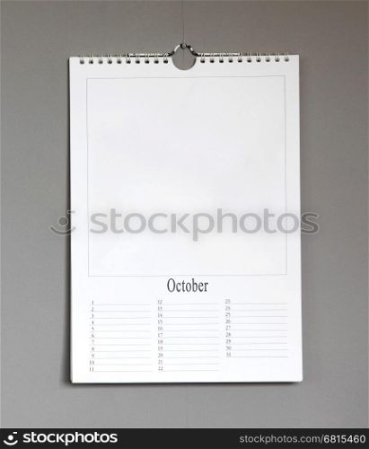 Simple old birthday calendar hanging on a grey wall, copy space - October