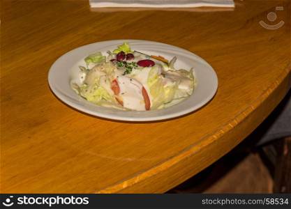Simple salad with sauce on a wooden table in the restaurant.