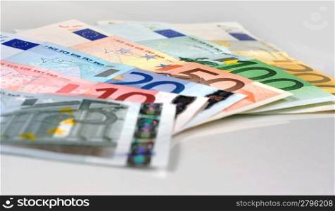 Simple shot of Euro banknotes of 200, 100, 50, 20, 10 Euros spread on a white table. Studio shot.