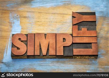 simplify word abstract in vintage letterpress wood type printing blocks stained by color inks against grunge wooden background