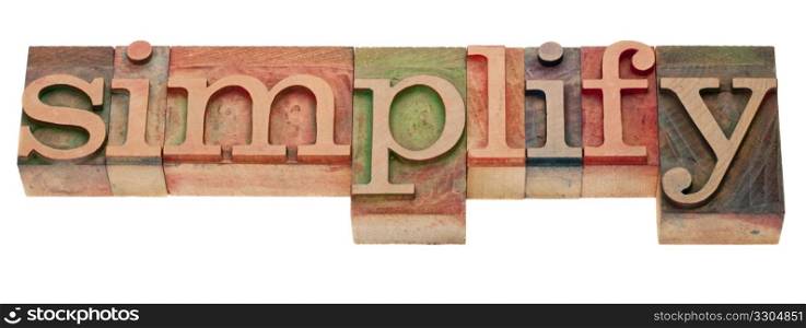 simplify- word in vintage wooden letterpress printing blocks, stained by color inks, isolated on white