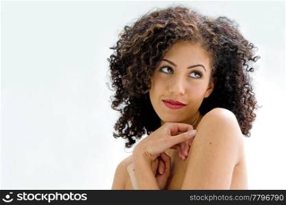 Sincere beautiful young woman with brown curly wild hair and bare shoulders, isolated
