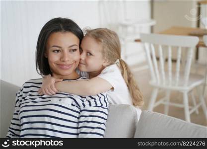 Sincere loving cute little daughter cuddling foster mother, showing love, tender feelings. Happy smiling mom and adopted preschool child girl hugs, embracing, enjoying weekend together at home.. Little preschool daughter cuddling foster mother, showing love, enjoying hugs together at home