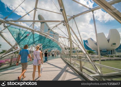 Singapore City, SINGAPORE - FEB 10, 2017: Caucasian tourist couple on helix bridge with Marina Bay Sands in background. Tourism in Singapore is major industry and contributor to Singapore economy.