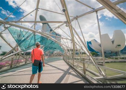 Singapore City, SINGAPORE - FEB 10, 2017: Single caucasian tourist on helix bridge with Marina Bay Sands in background. Tourism in Singapore is major industry and contributor to Singapore economy.