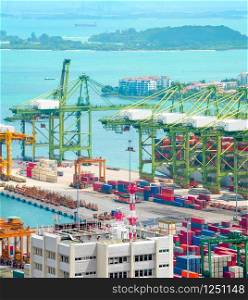 Singapore commercial port aerial view, freight cranes and containers at pier, islands and ships in background