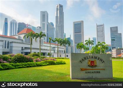 Singapore Parliament building, marble plate on green grass lawn, city skyline in background