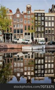 Singel canal historic terraced houses with reflection on water in the city of Amsterdam, Netherlands.