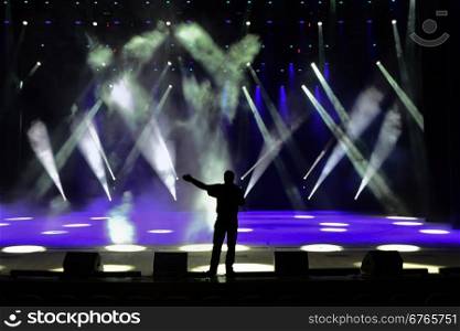 Singing man silhouette on a brightly lit concert stage