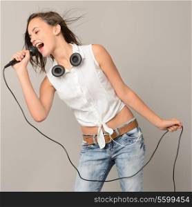 Singing teenage girl with microphone karaoke music on gray background