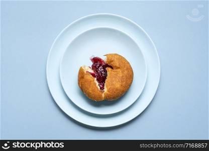 Single berliner doughnut sliced, with raspberry jam on blue plates and seamless background. Above view of homemade jelly donut. Famous german doughnut