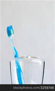 Single blue toothbrush in clear bathroom toothbrush holder.