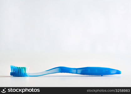 Single blue toothbrush lying face up on a white background.