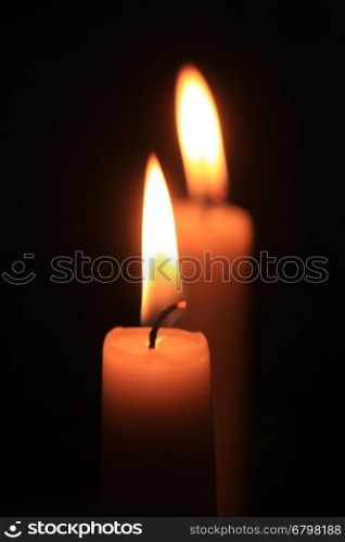 Single burning candle, close-up in the dark