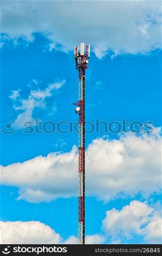 Single cell tower over background of a blue cloudy sky, vertical view.