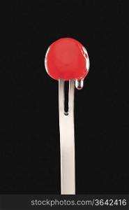 Single cocktail cherry in fork, black background