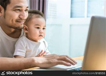 Single dad and son using laptop together happily. Technology and Lifestyles concept. Happy family and baby theme.